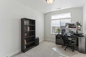 Home office with visible vents, baseboards, and light carpet