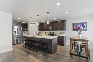 Kitchen featuring a kitchen bar, dark brown cabinetry, light wood-style floors, and appliances with stainless steel finishes