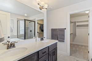 Full bath featuring tile patterned floors, a sink, double vanity, and a stall shower