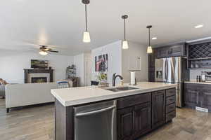 Kitchen featuring light wood finished floors, a sink, ceiling fan, light countertops, and appliances with stainless steel finishes