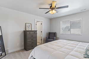 Bedroom with light carpet, baseboards, visible vents, and ceiling fan