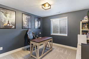 Carpeted office featuring a textured ceiling, baseboards, and visible vents