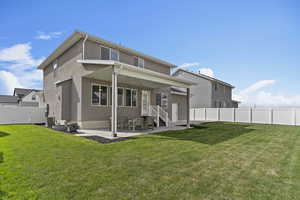 Back of house with stucco siding, a patio, a fenced backyard, and a lawn