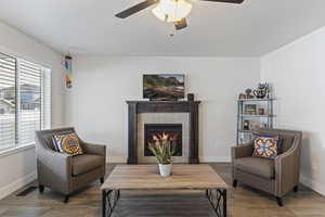 Living area featuring baseboards, a ceiling fan, a tile fireplace, and visible vents