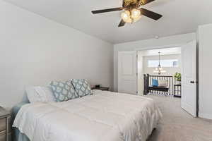 Bedroom with ceiling fan with notable chandelier and carpet