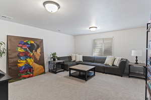 Carpeted living area featuring a textured ceiling and visible vents