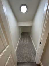Hallway featuring baseboards and dark carpet