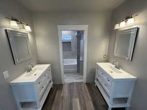 Full bathroom with a sink, wood finished floors, and two vanities