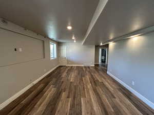 Below grade area with dark wood-style flooring, baseboards, visible vents, and recessed lighting