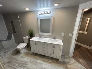 Bathroom featuring a sink, a shower stall, toilet, and double vanity