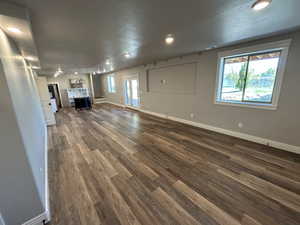 Unfurnished living room with recessed lighting, baseboards, and dark wood-style flooring