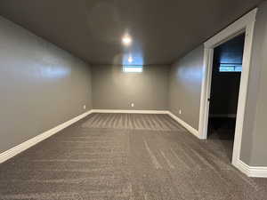 Basement with baseboards and dark carpet