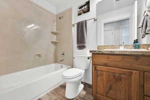 Bathroom with wood finished floors, vanity,  shower combination, and toilet