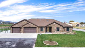 Ranch-style house featuring brick siding, a front lawn, concrete driveway, and a garage