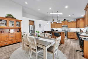 Dining room featuring a skylight, recessed lighting, light wood-style floors, and high vaulted ceiling