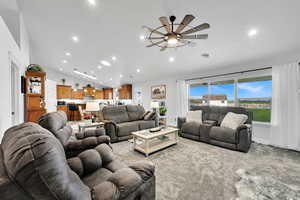 Carpeted living area with ceiling fan, baseboards, vaulted ceiling, and recessed lighting