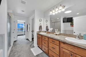 Full bath with visible vents, a sink, a shower stall, and double vanity