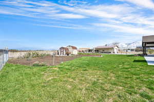 View of yard featuring a storage shed, a mountain view, fence, and an outdoor structure