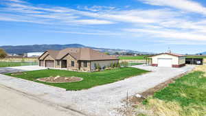 Ranch-style house featuring fence, an outdoor structure, a detached garage, a front yard, and a mountain view
