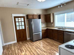 Kitchen featuring stainless steel appliances, laminate flooring and concrete countertops