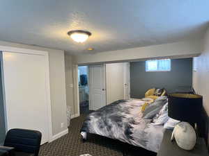 Bedroom with dark carpet, baseboards, and a textured ceiling