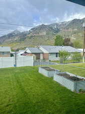 View of yard with fence, a vegetable garden, and a mountain view