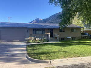 Raised ranch with metal roof, a front lawn, concrete driveway, a mountain view, and a garage