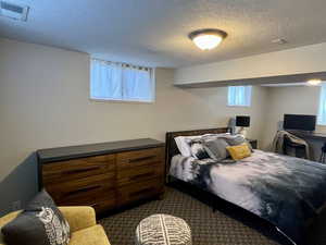 Bedroom featuring dark carpet, a textured ceiling, and visible vents