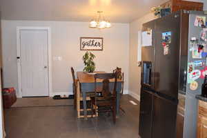 Dining room featuring dark tile patterned floors, baseboards, and an inviting chandelier