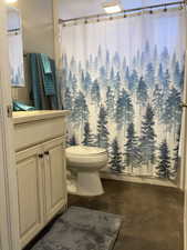 Bathroom featuring concrete flooring, toilet, vanity, and curtained shower