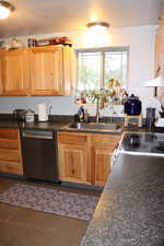 Kitchen with dark countertops, under cabinet range hood, a sink, and appliances with stainless steel finishes