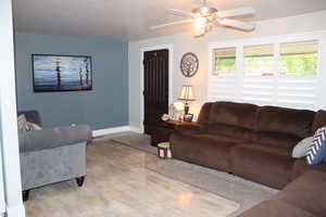 Living room with baseboards, a ceiling fan, and wood finished floors
