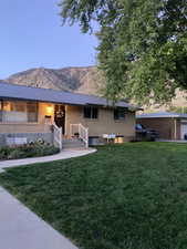 View of front facade with brick siding, a mountain view, metal roof, and a front yard