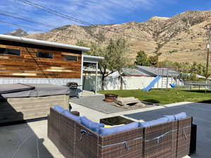 View of patio featuring a fenced backyard, a grill, a mountain view, a playground, and a hot tub