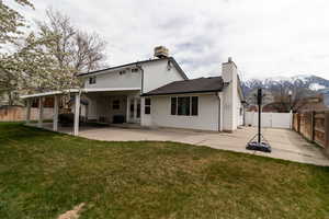 Back of house featuring a fenced backyard, a chimney, a patio, and a lawn