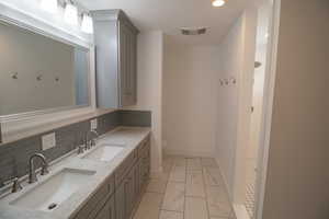 Bathroom with marble finish floor, a sink, visible vents, and double vanity