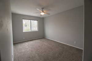 Spare room with ceiling fan, baseboards, and carpet
