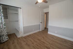 Unfurnished bedroom featuring baseboards, a ceiling fan, wood finished floors, and a closet