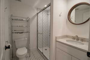 Bathroom with a shower stall, visible vents, toilet, and vanity