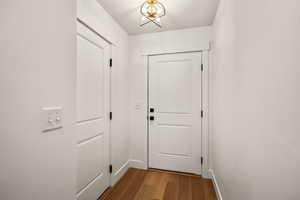 Doorway with wood finished floors and a chandelier