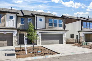 View of front of house with stone siding, board and batten siding, concrete driveway, and a garage