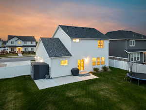 Rear view of house featuring a gate, a patio area, a trampoline, a fenced backyard, and stucco siding
