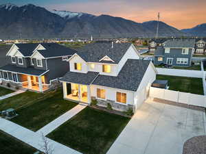 View of front of house with fence, concrete driveway, a porch, stone siding, and a mountain view