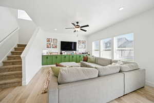 Living area with stairway, light wood-type flooring, ceiling fan, baseboards, and recessed lighting