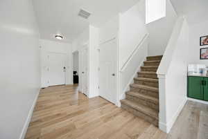 Stairway featuring wood finished floors, visible vents, and baseboards