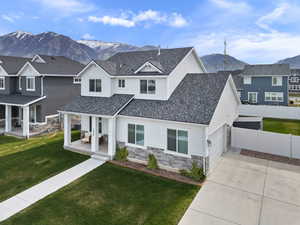 Modern inspired farmhouse with a front lawn, a mountain view, stone siding, fence, and concrete driveway