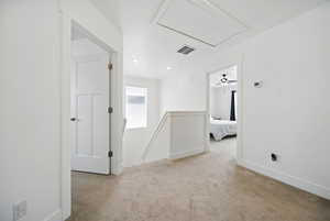 Carpeted spare room featuring attic access, visible vents, and baseboards