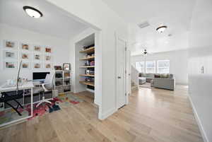 Office space with light wood-type flooring, baseboards, visible vents, and ceiling fan