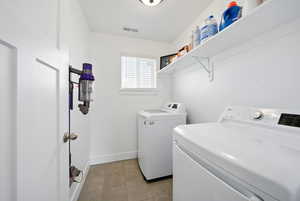 Clothes washing area featuring washing machine and dryer, baseboards, visible vents, laundry area, and light tile patterned floors