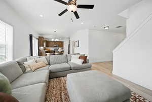 Living room featuring recessed lighting, visible vents, light wood-type flooring, baseboards, and ceiling fan with notable chandelier